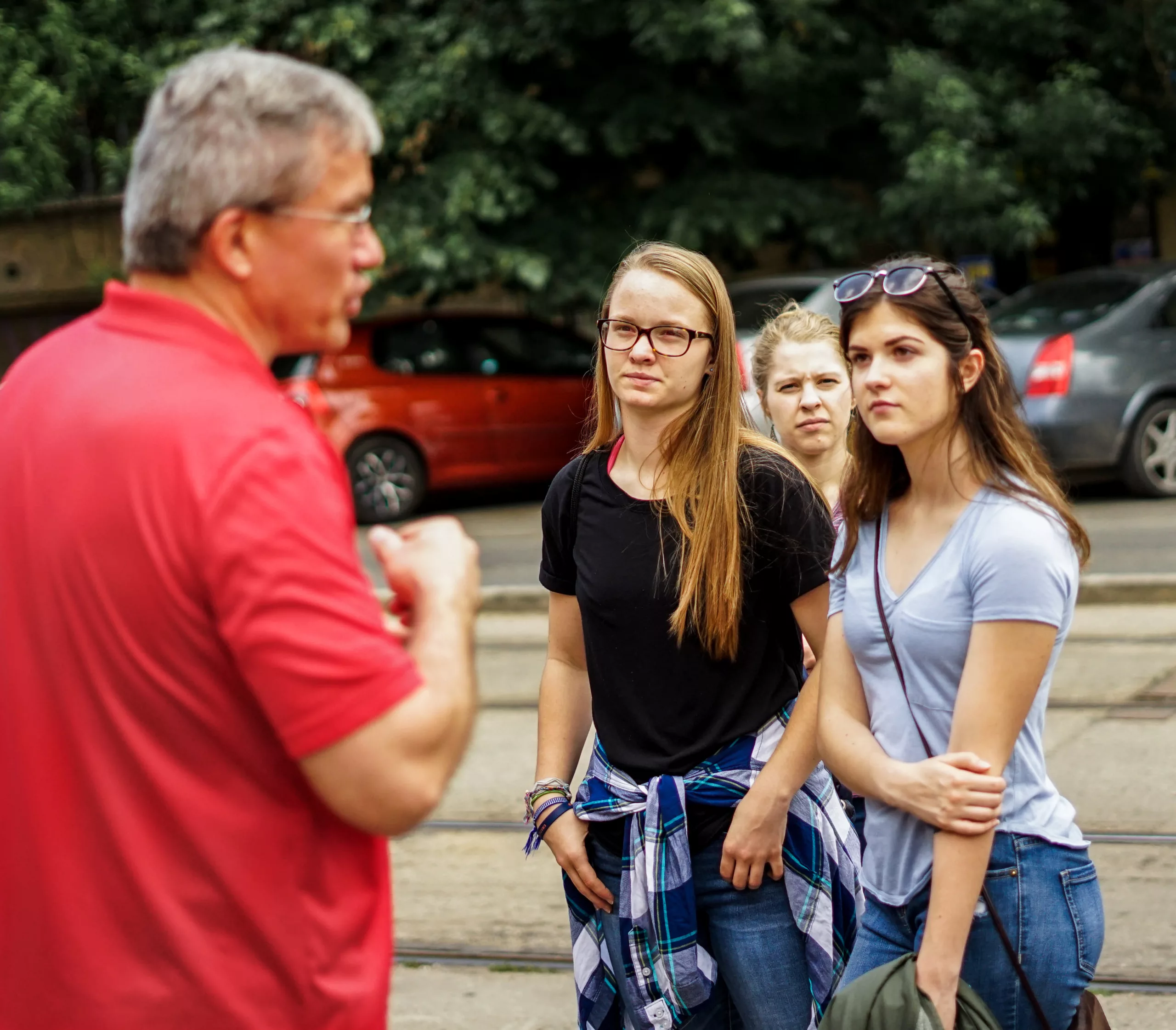 Street ministry A man in a red t-shirt is seen in the foreground talking to three young women dressed casually.